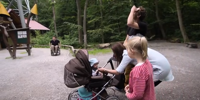 Rollstuhlfahrer und Familie mit kleinem Kind und Kinderwagen